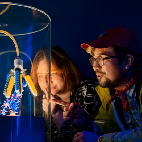 Two young museum goers pointing and looking at specimen